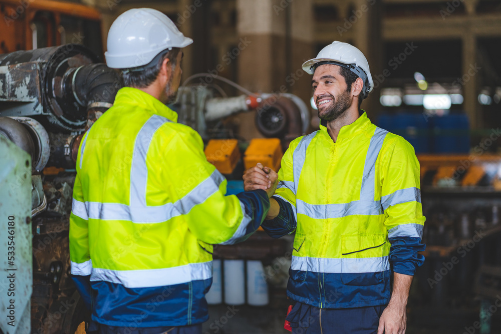 Caucasian factory engineer talking and shaking hands on business cooperation agreement. Successful hand shaking after good deal, workers handshaking each other at heavy industrial production line. Caucasian factory engineer talking and shaking hands on business cooperation agreement. Successful hand shaking after good deal, workers handshaking each other at heavy industrial production line.
