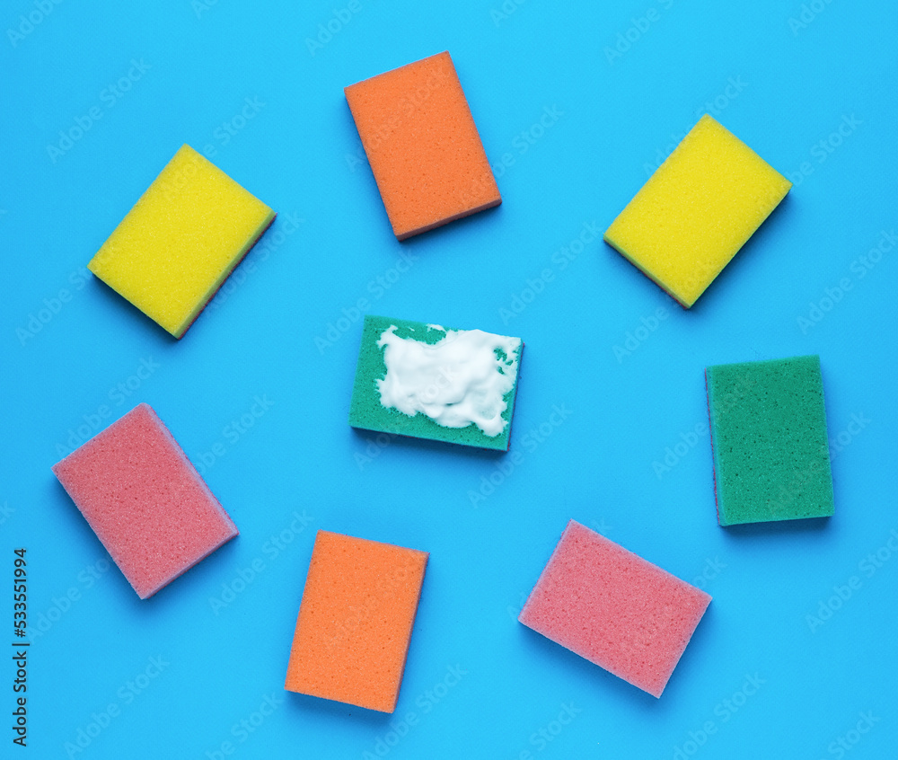 Multi-colored set of bright foam sponges on a blue background. Minimal concept of washing and cleaning. Multi-colored set of bright foam sponges on a blue background. Minimal concept of washing and cleaning.