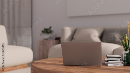 Laptop on minimal wood coffee table in cozy minimal home or apartment living room.