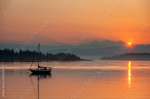 Colorful Sunrise Over Mt. Baker With a Sailboat in the Foreground.  Beautiful calm morning in the San Juan Islands as the majestic Mt. Baker looms in the background. © LoweStock