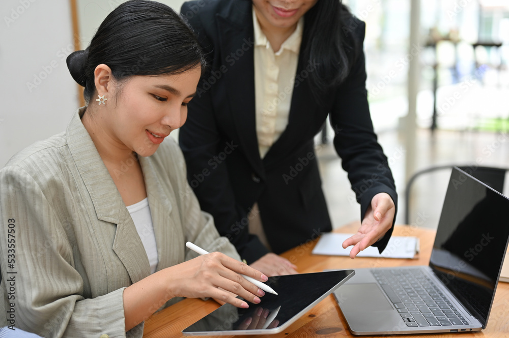 Asian female boss checking her meeting schedule on tablet with her assistant. Asian female boss checking her meeting schedule on tablet with her assistant.