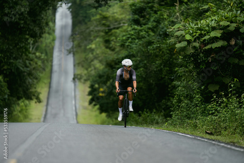Groups of cyclists riding road bikes in the morning are climbing. © torwaiphoto