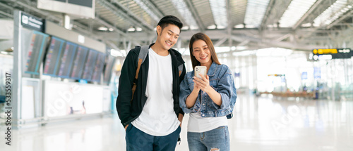 New normal travel bubble and social distancing concept.Traveler man and woman smiling without face mask and waiting to board at terminal airport.Holiday vacation safety traveling abroad ideas concept