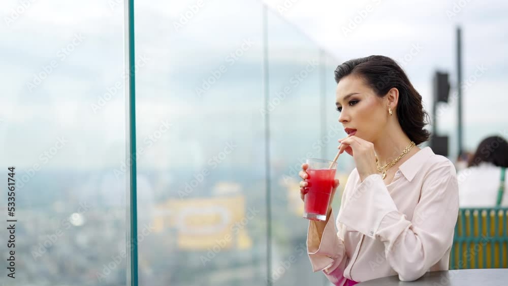 4K Confident Caucasian woman enjoy outdoor lifestyle drinking cocktail while waiting for meeting with boyfriend at skyscraper rooftop restaurant and bar with looking to city skyline at summer sunset. 4K Confident Caucasian woman enjoy outdoor lifestyle drinking cocktail while waiting for meeting with boyfriend at skyscraper rooftop restaurant and bar with looking to city skyline at summer sunset.