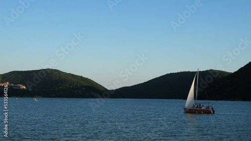 Company resting on an orange sailboat on the lake in summer