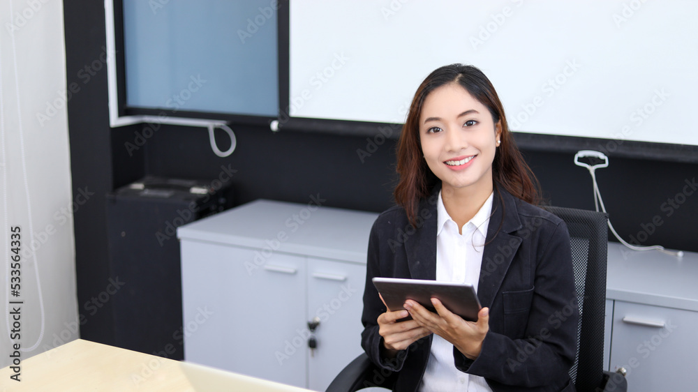 Smiling Asian businesswoman using tablet for work and Cute girl searching for some data and concentrate on her tablet in her office. Smiling Asian businesswoman using tablet for work and Cute girl searching for some data and concentrate on her tablet in her office.