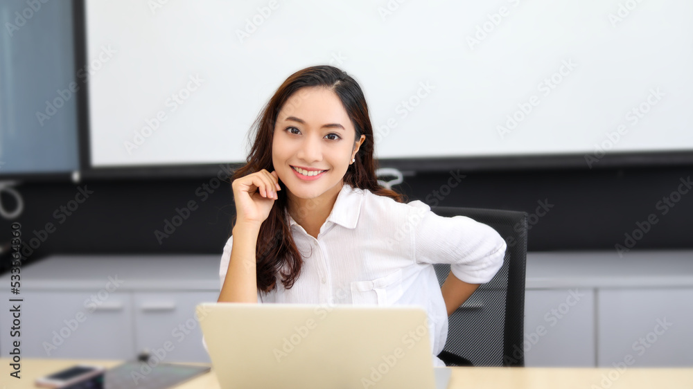 Asian businesswoman smiling and using her laptop for work and doing internet research in her office. Asian businesswoman smiling and using her laptop for work and doing internet research in her office.