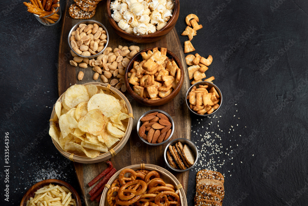 Fototapeta premium Assortment of salty snacks on dark background.