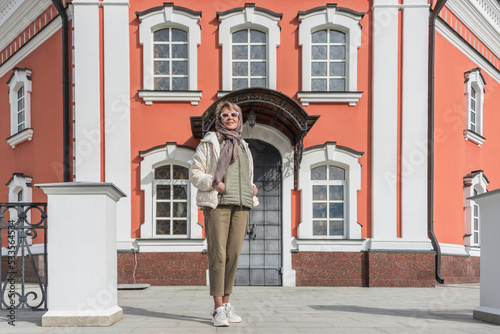 Portrait of a mature woman in autumn clothes on the background of ancient architecture walls.