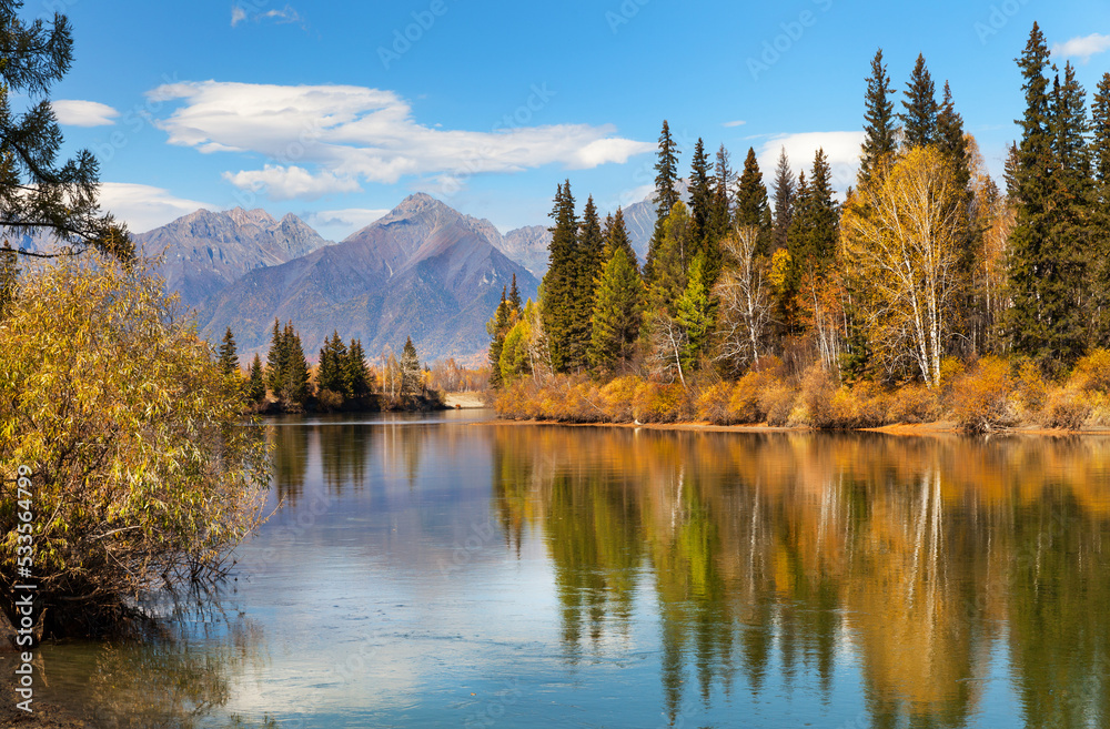 Fototapeta premium Beautiful autumn calm landscape with the Eastern Sayan Mountains and yellowed trees on the banks of the Irkut River. Baikal region, Buryatia, Tunka Valley, Nugan village