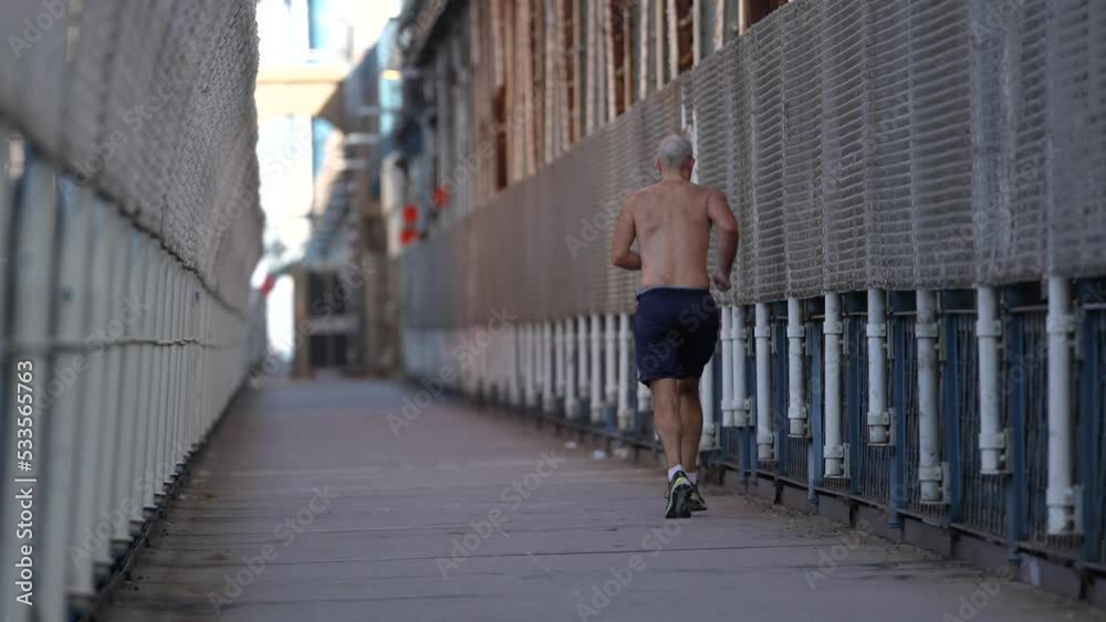 4K video with a bare-chested man running and jogging on the pedestrian path from Manhattan Bridge. Sport is good at any age. 4K video with a bare-chested man running and jogging on the pedestrian path from Manhattan Bridge. Sport is good at any age.