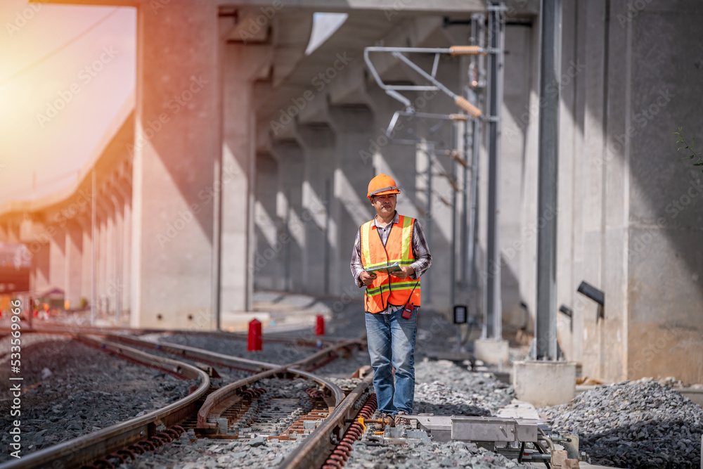Engineer under inspection and checking construction process railway switch and checking work on railroad station .Engineer wearing safety uniform and safety helmet in work. Engineer under inspection and checking construction process railway switch and checking work on railroad station .Engineer wearing safety uniform and safety helmet in work.