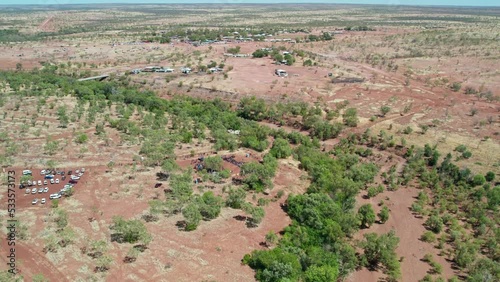 Forward moving aerial view of the cermony at the start of the Freedom Day Festival and the community of Kalkaringi in the background, Northern Territory, Australia. 26 August 2022. photo