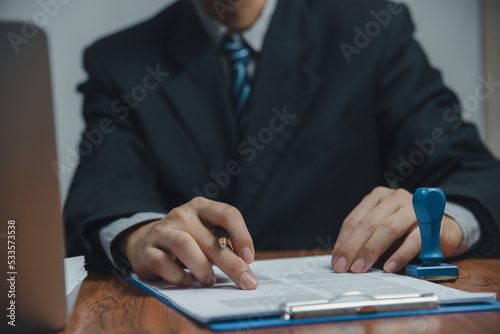 Businessman hand holding pen paperwork chart report and document financial graph investment marketing or tax insurance on desk.