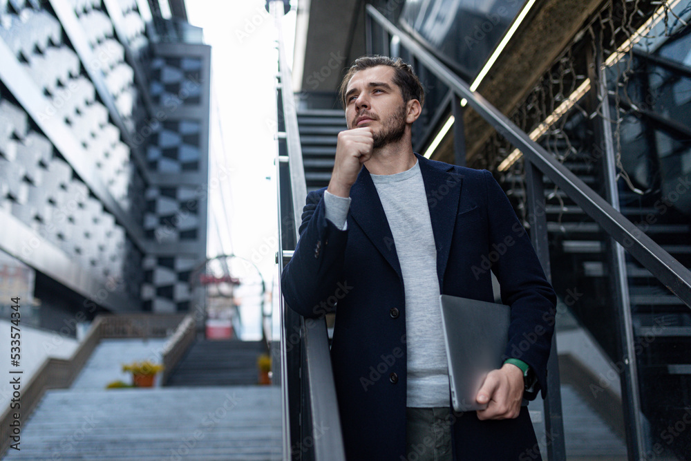pensive male head on the background of the city business center with a laptop in his hands, Concept business planning pensive male head on the background of the city business center with a laptop in his hands, Concept business planning