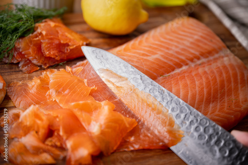 slicing gravlax, cured salmon, with knife photo