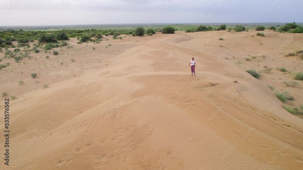 Aerial View Of Woman Walking Across Desert Landscape. Static Shot Aerial View Of Woman Walking Across Desert Landscape. Static Shot