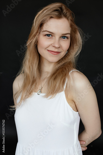 Vertical portrait of positive, smiling and cheerful young blonde long haired woman with shiny skin in top and necklace