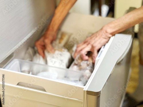 冷凍庫をあさる高齢女性の手