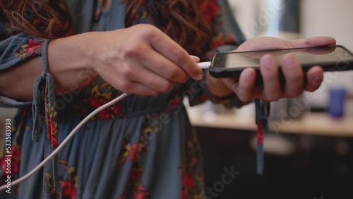 Close up, female hand plugging charger into phone