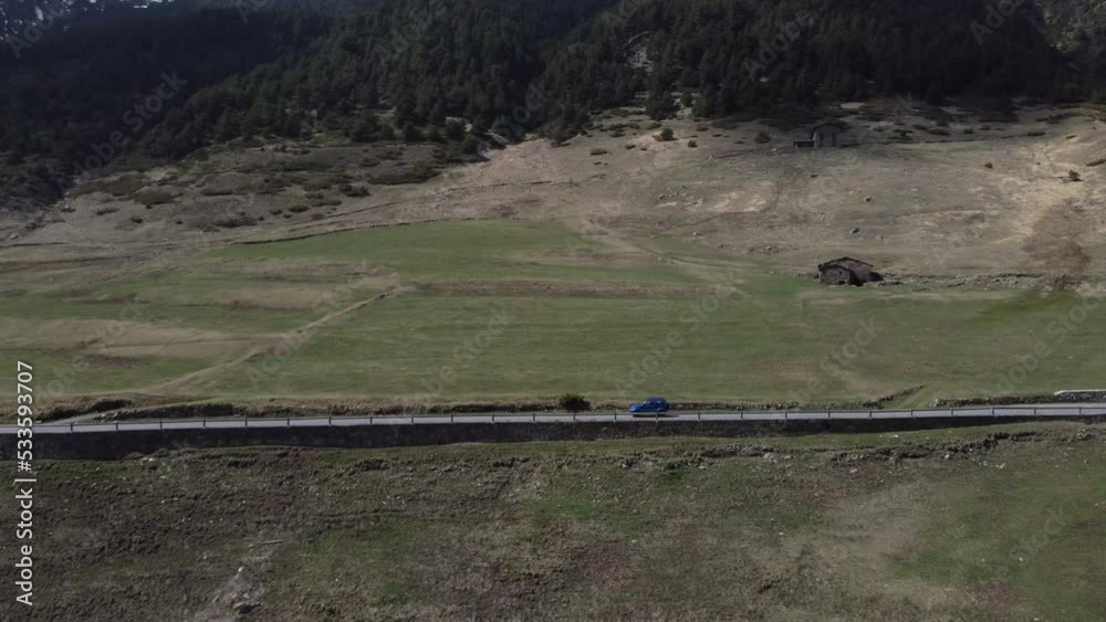 Isolated 4x4 blue car driving along solitary mountain road. Aerial sideways Isolated 4x4 blue car driving along solitary mountain road. Aerial sideways