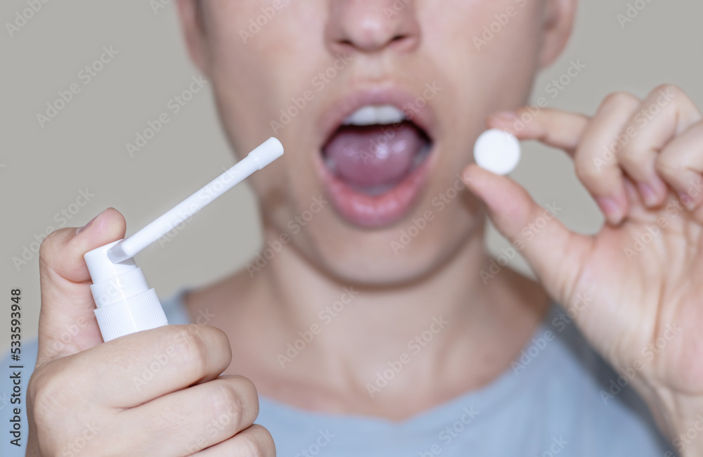 sore throat and runny nose treatment. woman using lozenge candy spray for red painful throat or