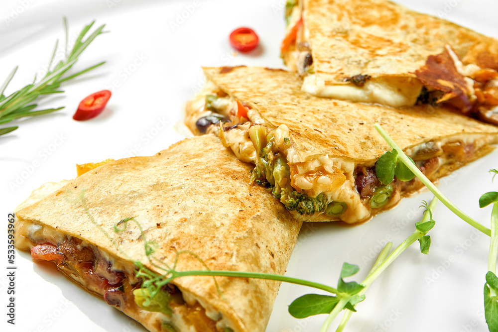 Quesadilla with cheese and vegetables in a white plate. Close-up, selective focus. White background. Quesadilla with cheese and vegetables in a white plate. Close-up, selective focus. White background.