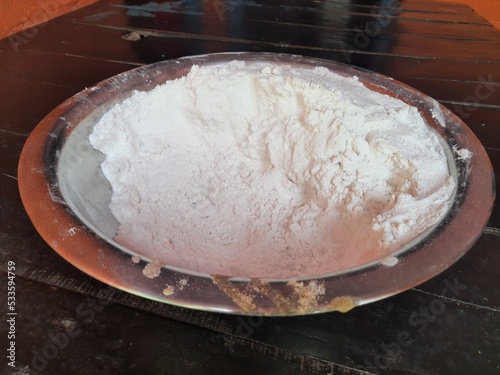 Rice flour in bowl. Many food items are made from rice flour, such as roti, sweets, puwa, dish. In India, offerings of worship are also made from it. photo