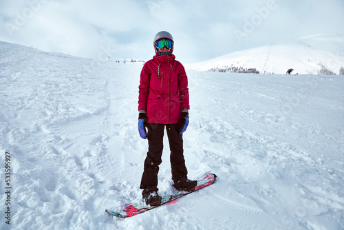 Caucasian woman snowboarding on empty track of Carpathians, Ukraine ski resort on a beautiful sunny winter day