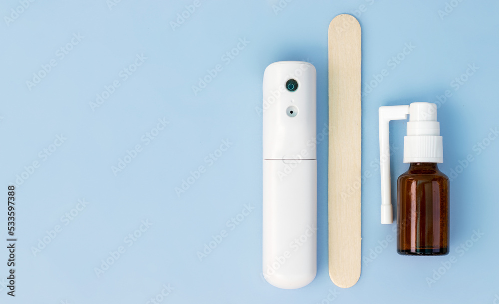 sore throat treatment concept.isolated on blue medicinal background one wooden spatula for neck checking red pain.electronic thermometer spray lozenges surgical gloves.flu virus bacteria autumn cold sore throat treatment concept.isolated on blue medicinal background one wooden spatula for neck checking red pain.electronic thermometer spray lozenges surgical gloves.flu virus bacteria autumn cold