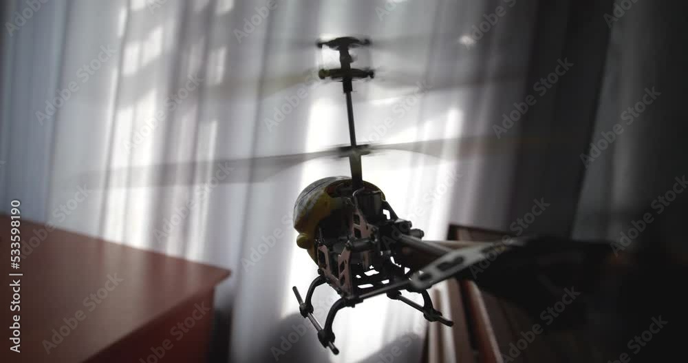 Point of view video of toy yellow radio-controlled model helicopterflying and landing on children's desk with drawings, pencils and scissors. Window is in the background. Slow motion 50 fps Point of view video of toy yellow radio-controlled model helicopterflying and landing on children's desk with drawings, pencils and scissors. Window is in the background. Slow motion 50 fps