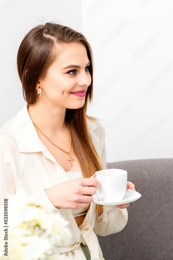 Female caucasian client with a cup of coffee in his hands smiling at a doctor's appointment Female caucasian client with a cup of coffee in his hands smiling at a doctor's appointment