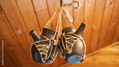 Two earthenware jars with spouts are suspended on a rope. Ceramic tableware.