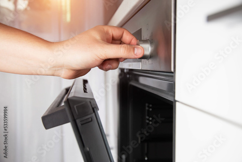 A man's hand selects a function in a modern electric oven and sets the child protection. Close-up