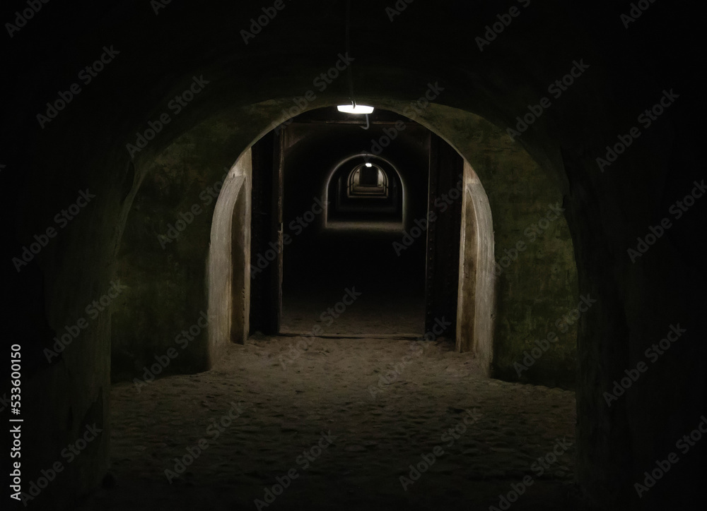 A long dark tunnel of a bomb shelter with a light at the end of the tunnel. Shelter of a bomb shelter in wartime.