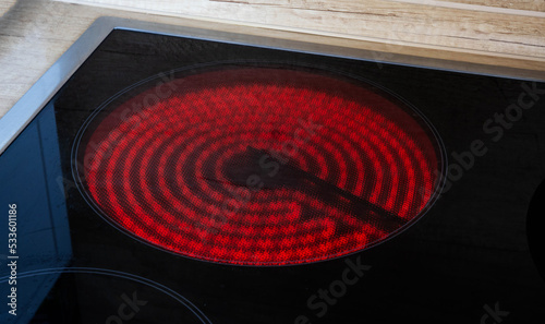 Incandescent burner of an induction hob in the kitchen, close-up. Black ceramic hob, modern stove photo