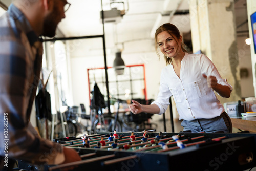 Colleagues having fun at work. Businessman and businesswoman playing table soccer..