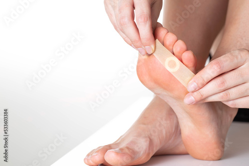 A girl sticks a medical plaster for plantar warts on her leg. Callus treatment. Copy space for text