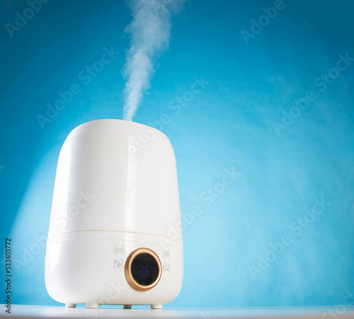 Modern device for air humidification on a blue background. Wet Steam Humidifier. Copy space for text photo