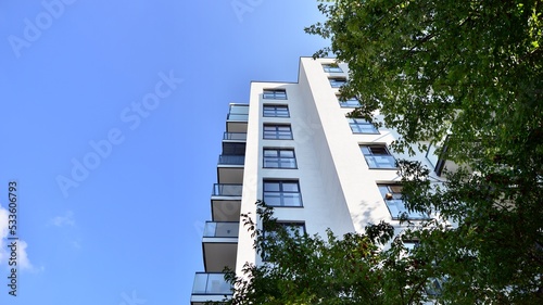 Modern residential building with new apartments in a green residential area. Eco architecture. Green tree and new apartment building. The harmony of nature and modernity.