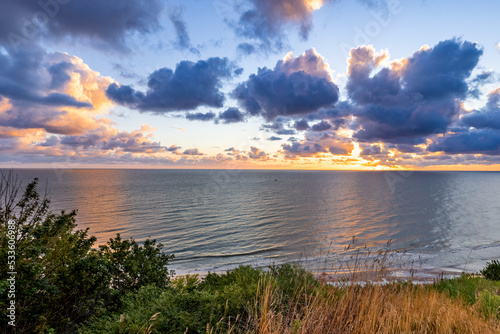 Fototapeta Naklejka Na Ścianę i Meble -  Sunrise at Baltic Sea beach. Cloudy weather, small waves, no people. Sun flares and water reflection