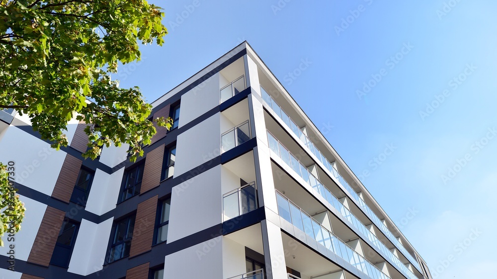 Modern residential building with new apartments in a green residential area. Eco architecture. Green tree and new apartment building. The harmony of nature and modernity. Modern residential building with new apartments in a green residential area. Eco architecture. Green tree and new apartment building. The harmony of nature and modernity.