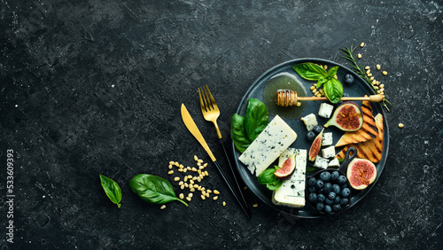 Blue cheese, figs, blueberries and honey on a plate. On a concrete background. Top view.