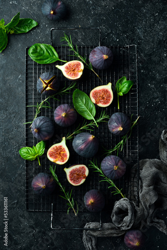 Figs and leaves on a dark stone table. On a dark background. Space for text. Top view.