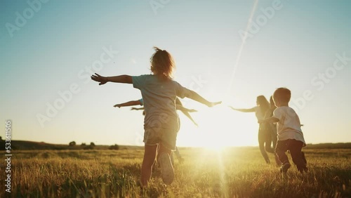 kids run in the park at sunset. friendly family children camp kid dream concept. a group of children run on the grass at fun the rays of the sun silhouette. childhood sunset dream teamwork concept photo