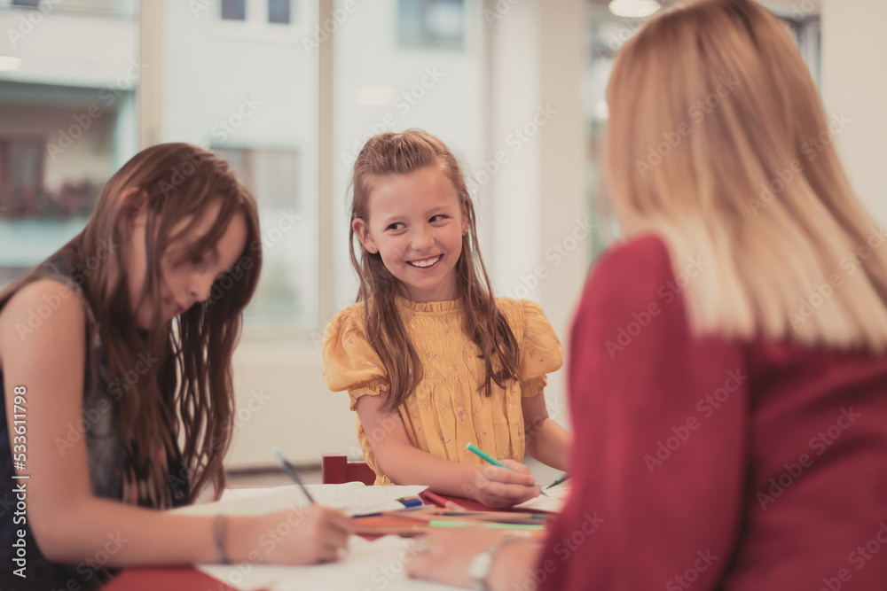 Creative kids during an art class in a daycare center or elementary school classroom drawing with female teacher. Creative kids during an art class in a daycare center or elementary school classroom drawing with female teacher.
