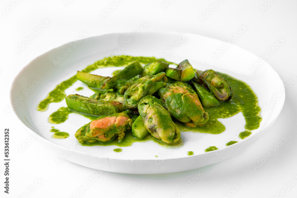 Cooked mussels in green sauce. Balanced, nutritious, tasty and nutritious food. Ready-made menu for a restaurant or for delivery. Dish in a white plate isolated on a white background. Cooked mussels in green sauce. Balanced, nutritious, tasty and nutritious food. Ready-made menu for a restaurant or for delivery. Dish in a white plate isolated on a white background.