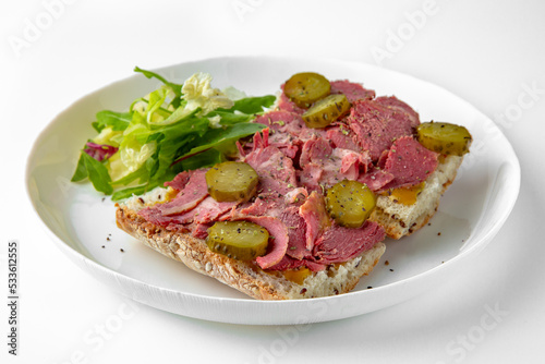 Sandwich with beef pastrami with pickles. Balanced, nutritious, tasty and nutritious food. Ready-made menu for a restaurant or for delivery. Dish in a white plate isolated on a white background.