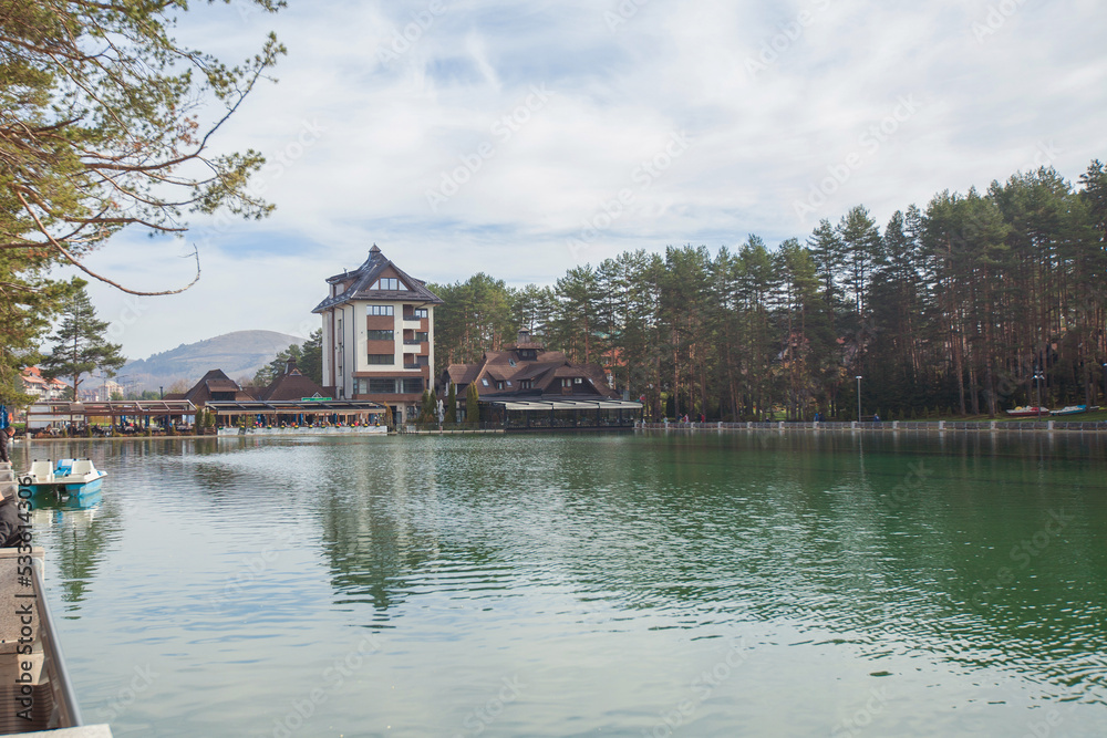 Lake in the touristic center surrounded pine forest in park, an autumn sunny day. Pleasant place for relaxing. Mountain Zlatibor, Serbia. Lake in the touristic center surrounded pine forest in park, an autumn sunny day. Pleasant place for relaxing. Mountain Zlatibor, Serbia.
