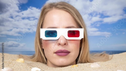 Woman buried in sand on beach with 3d glasses photo